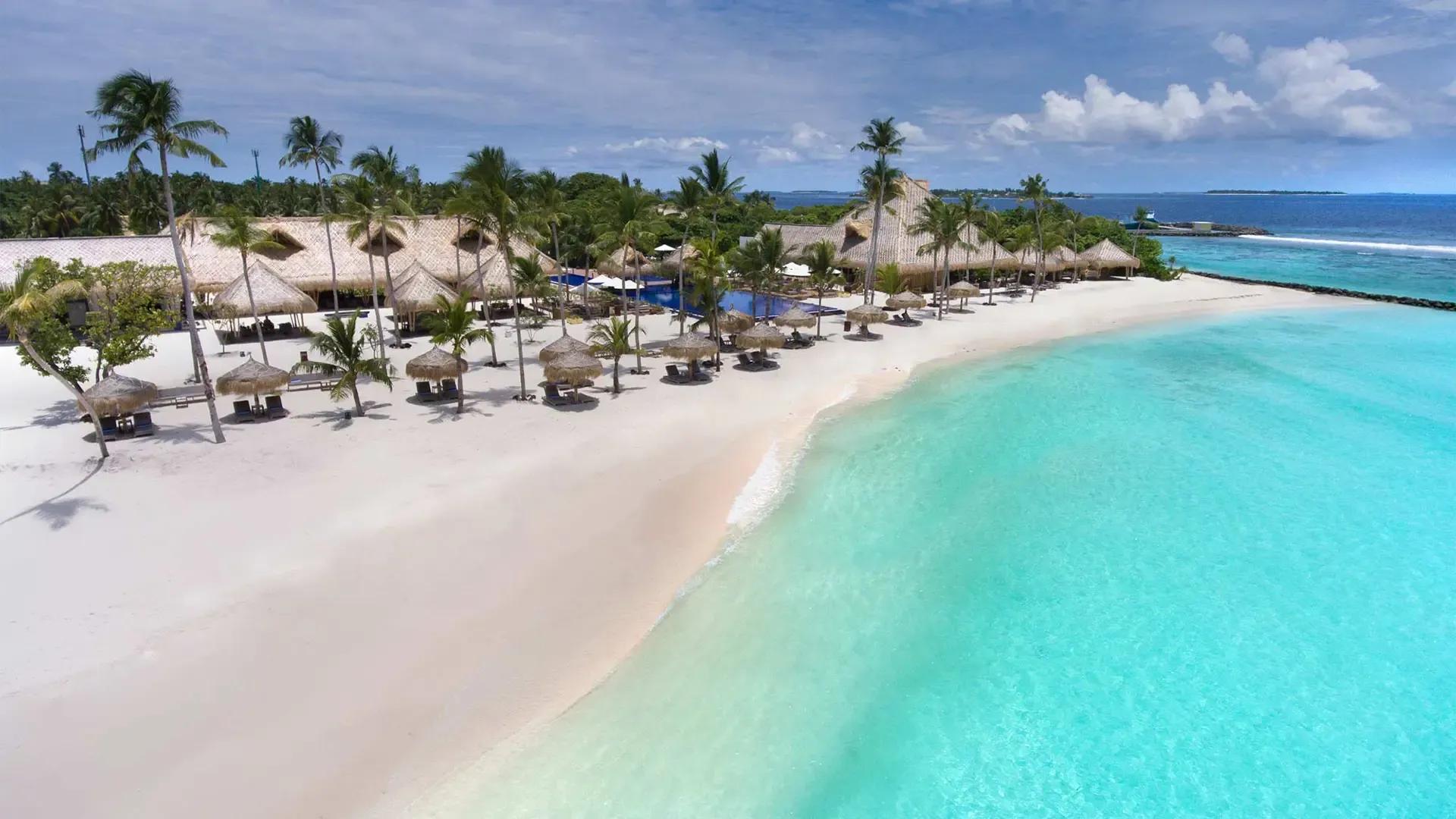 Пляж с пальмами и бирюзовая лагуна Emerald Maldives с высоты под небом с облаками, атолл Раа, Мальдивы в декабре