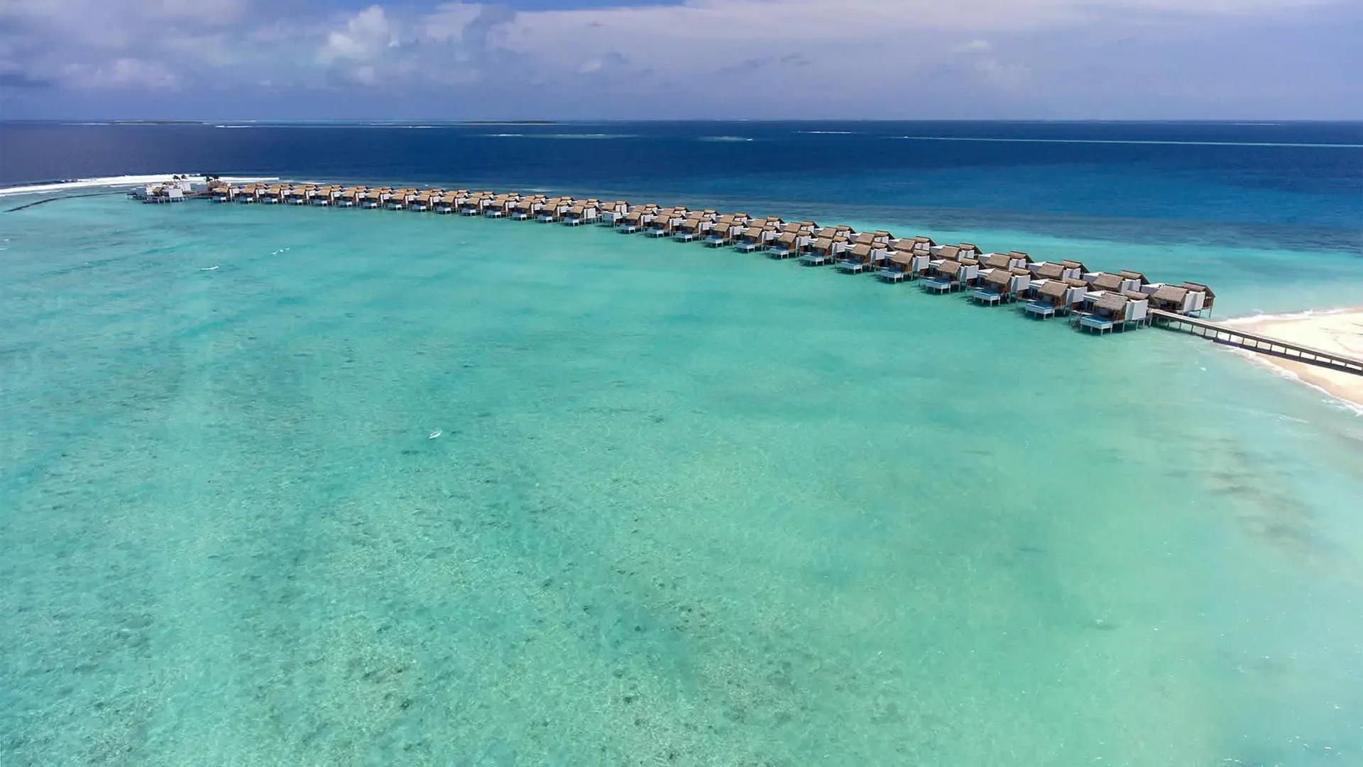 Ряд вилл на воде Emerald Maldives над лагуной с высоты, атолл Раа