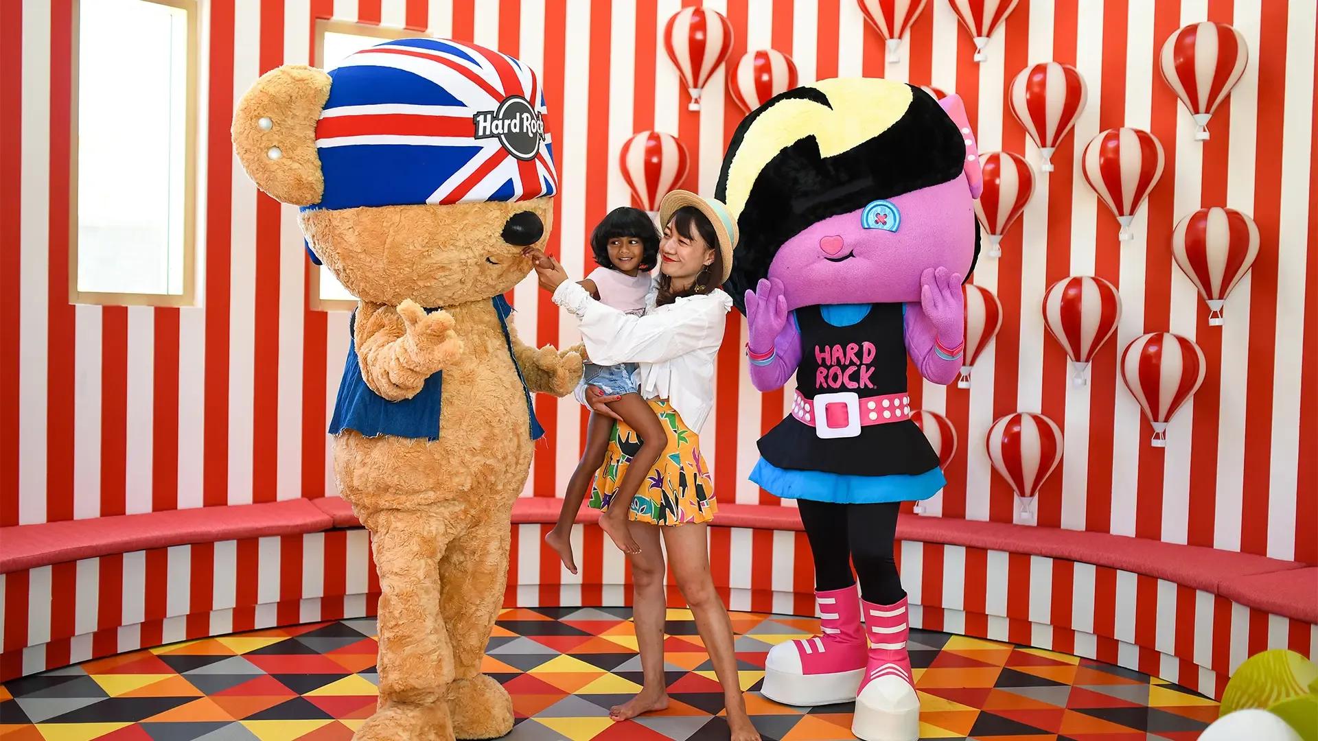 Детский клуб: ростовые маскоты играют с детьми в зале с полосатыми стенами