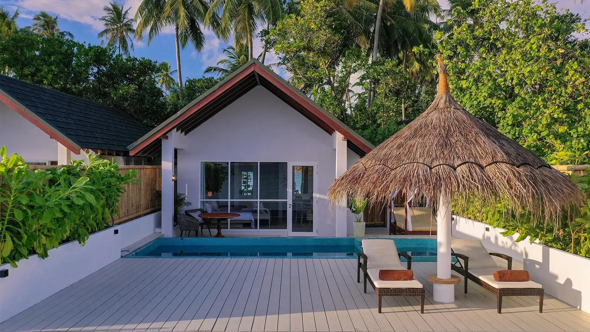 Sunrise Beach Pool Villa на Малахини Куда Бандос: бассейн, лежаки под соломенным зонтом и сад