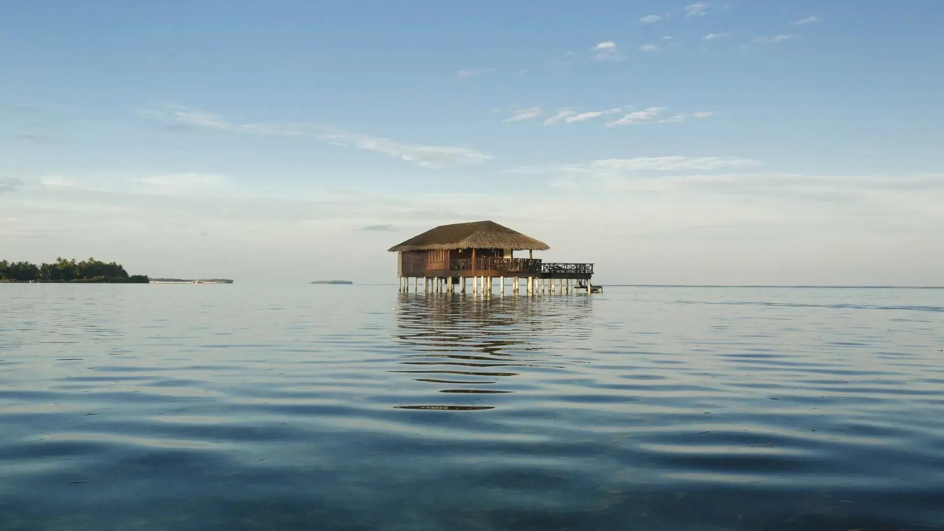 Вилла на воде посреди зеркальной глади под пасмурным небом, Medhufushi, атолл Меему