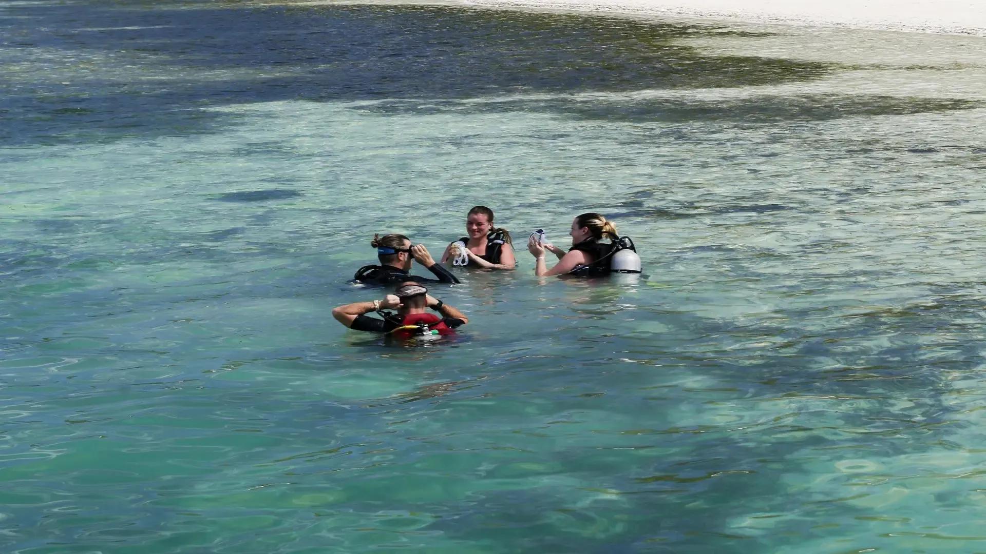 Дайверы на поверхности над рифом Medhufushi, зеленоватая вода с планктоном, атолл Меему