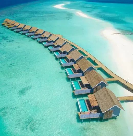 Ряд водных вилл Курамати уходит от берега в лагуну, рядом песчаная коса