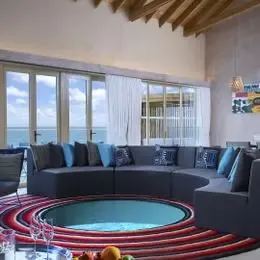 Гостиная Rock Star Villa: круглый диван вокруг встроенного бассейна и обеденная зона у окон