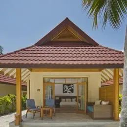 Beachfront Deluxe Bungalow в Курумбе снаружи: терраса с креслами под черепичной крышей у пальм