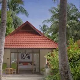 Deluxe Bungalow в Курумбе снаружи: домик с красной черепицей и террасой среди пальм