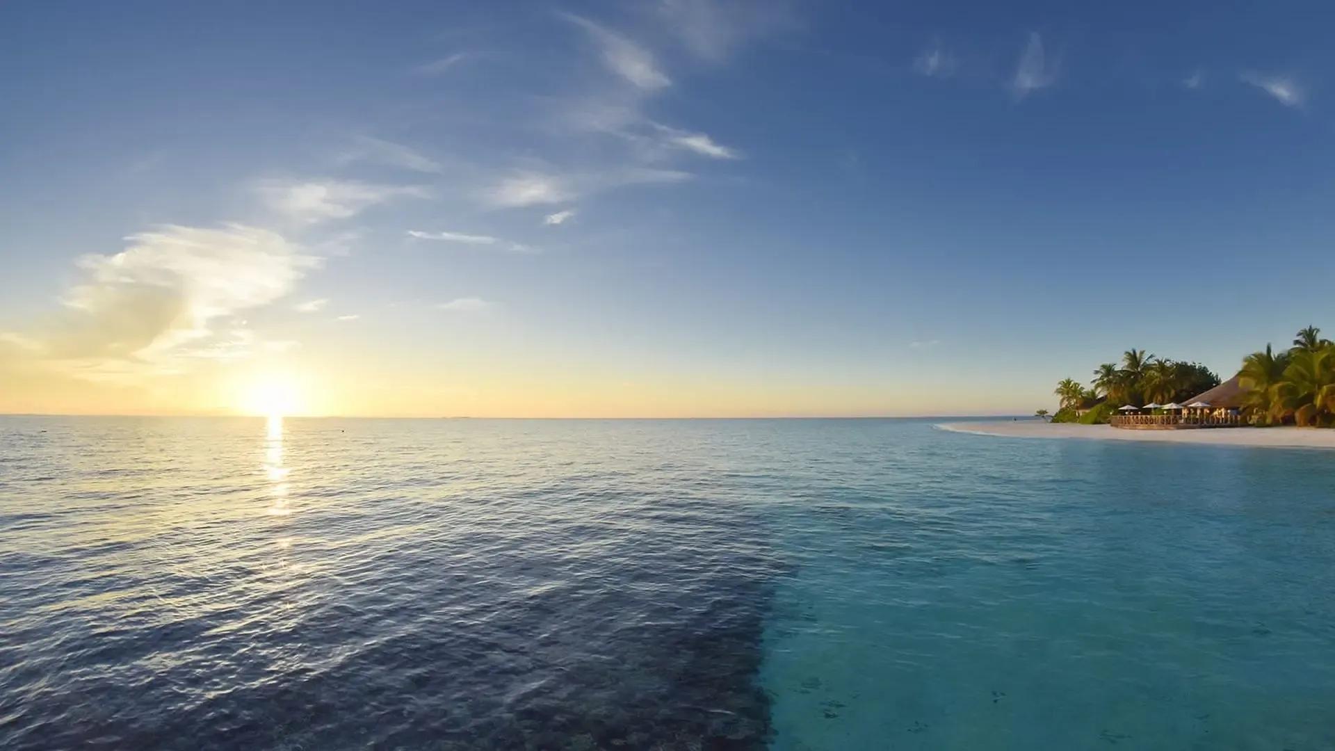 Солнце у горизонта над гладкой лагуной, вдали остров Angaga Island Resort